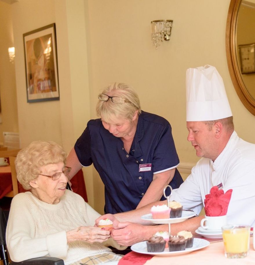 Chef and team member sitting with resident at dining table