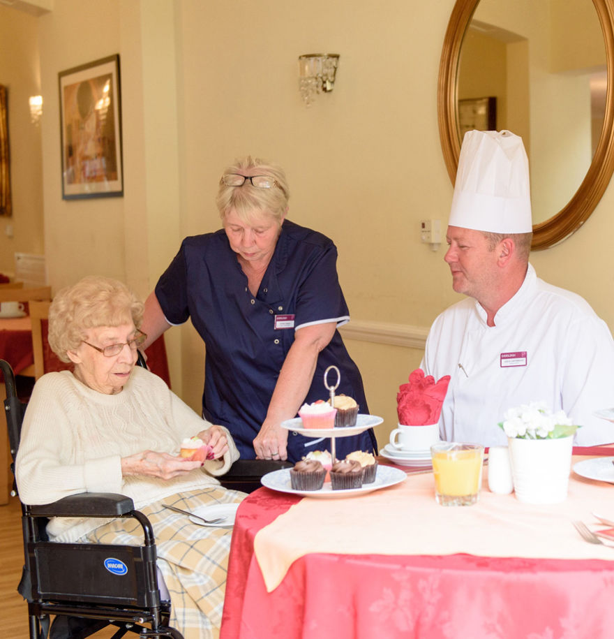 Chef and team member sitting with resident at dining table